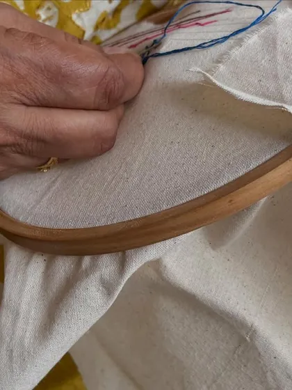 A close-up of a student's hands at work. The dedication and focus required for embroidery is a skill in itself, teaching patience and attention to detail.