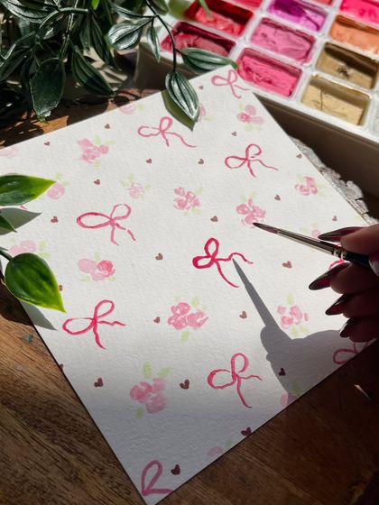 Painting the delicate bow and flower pattern on the paper before folding it into an envelope.