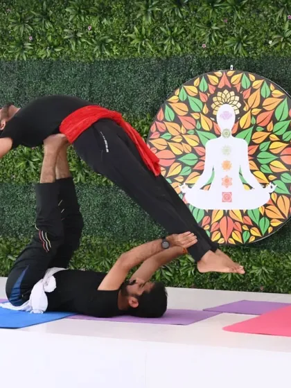 A demonstration of Acro Yoga, where one practitioner supports another in a therapeutic flying pose. This practice builds trust, communication, and a playful spirit.