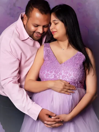 A close-up shot capturing the tender connection between the expecting couple. Dressed in a lovely lavender gown, the mom-to-be shares a quiet moment with her partner.