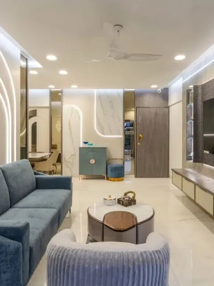 A modern living room where comfort is key. The space features a plush blue sofa, a stylish TV unit, and arched wall panels with integrated lighting, creating a soft and contemporary ambiance.