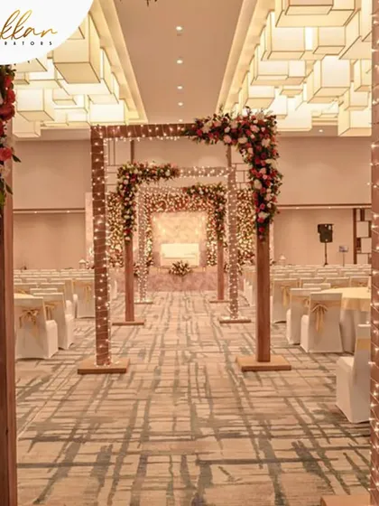 A beautiful indoor wedding aisle created with wooden arches wrapped in fairy lights and topped with floral arrangements. This design brings a rustic yet elegant feel to an indoor ceremony.