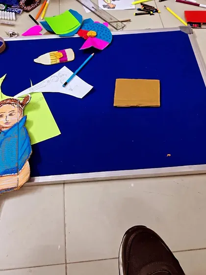A work in progress. A volunteer works on a large format visual aid, carefully cutting and pasting elements to bring a story to life for students.