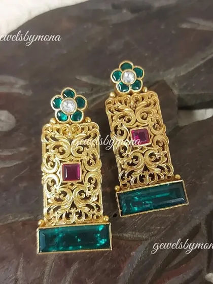 A closer look at the detailed craftsmanship of these Dakshinaya earrings. The delicate jaali work in gold is complemented by the rich green and red stones, making them a timeless piece of art.