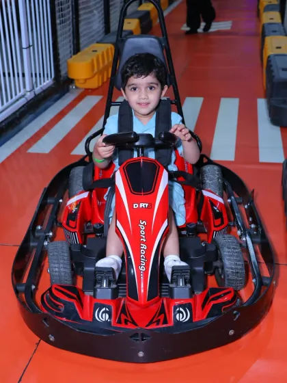 A young boy in a blue shirt gets buckled in for a safe and exciting ride on our go-kart track.