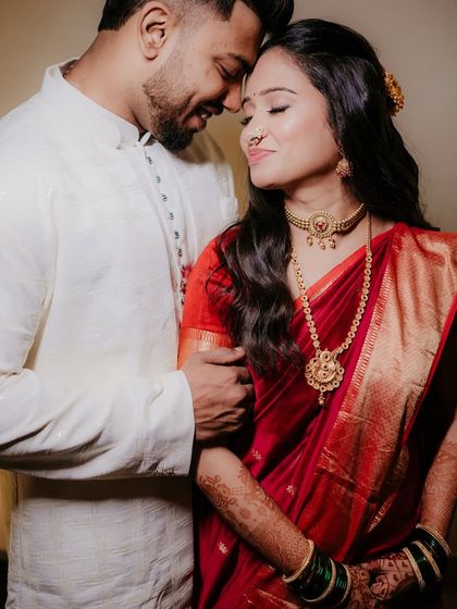 A romantic close-up of the couple, their eyes closed in a moment of serene connection. The bride's red saree adds a pop of vibrant color.