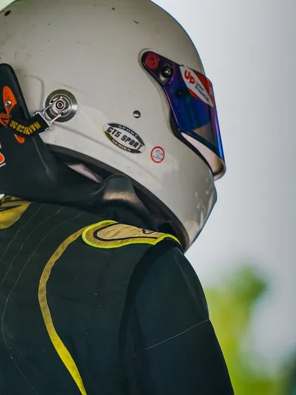 A close-up of a driver's helmet and HANS device, essential safety equipment for high-speed formula racing.