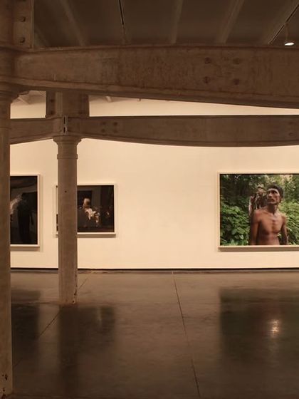A visitor contemplates an exhibition at Project 88 gallery. The preserved industrial columns punctuate the large, open space, creating a rhythm that guides movement without dictating a specific path.
