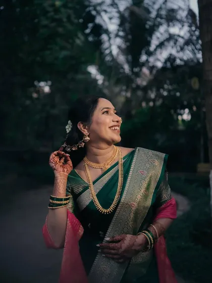 A joyful, candid shot of the bride in her green silk saree. Her natural, glowing makeup looks perfect in the outdoor setting.