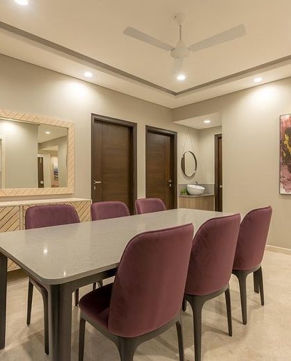 A spacious dining area designed for entertaining. The chevron-patterned sideboard and bold purple chairs add a touch of modern glamour to the room.