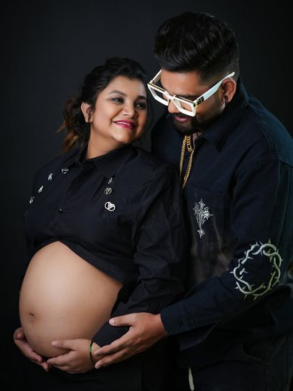 A loving couple's portrait with a focus on the bare belly. The shared look between them speaks to their partnership and excitement on this journey together.