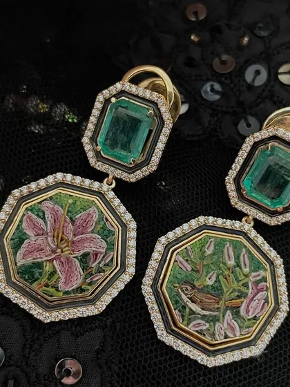 The stories of the Lilium continue with this Art Deco inspired pair. One earring shows the bud and bird, the other the full bloom, handcrafted in 18k gold with Zambian emeralds and black enamel.