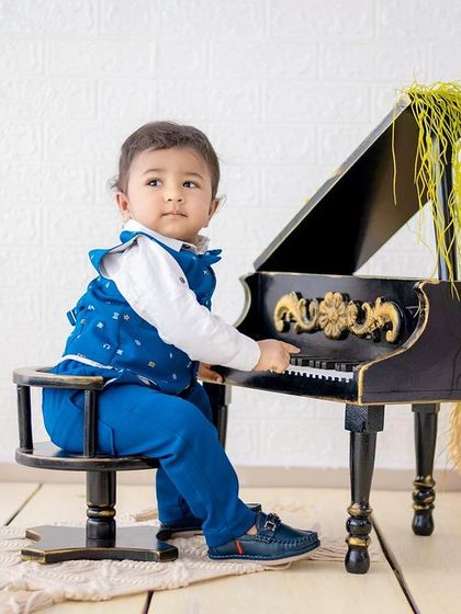 A stylish portrait of a little boy in a blue suit at our miniature grand piano.