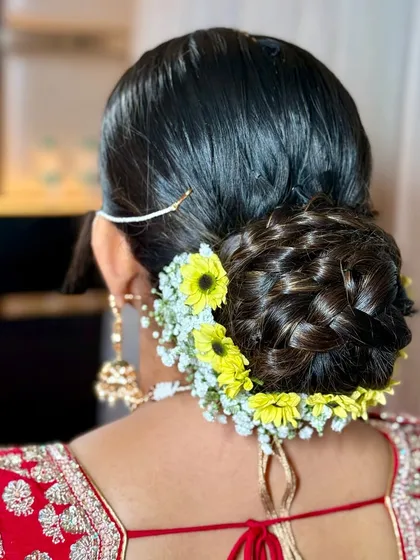 A detailed view of the braided bridal bun, adorned with fresh yellow and white flowers for a pop of color.