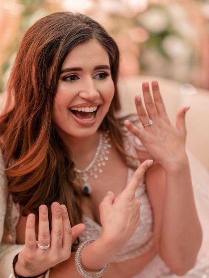 The bride excitedly shows off her and her new fiancé's rings to the camera, a moment of pure happiness.