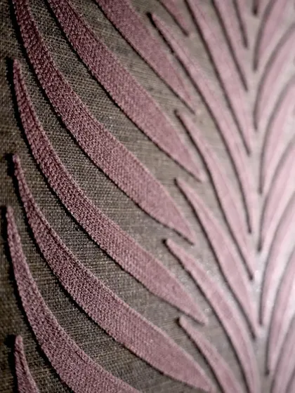 The 'Ornementa' wallcovering by Casamance uses a warm color harmony inspired by palaces. This detailed view shows the elegant plum shade and refined texture, capturing an atmosphere where time seems to stand still.