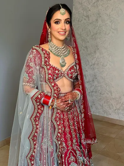 The full bridal look, showcasing the stunning red and mint green lehenga. The makeup is designed to be timeless and elegant.