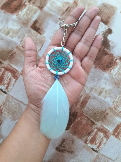 A simple and elegant dreamcatcher bag charm with a single, soft feather. This design is perfect for adding a touch of free-spirited bling to your bag.