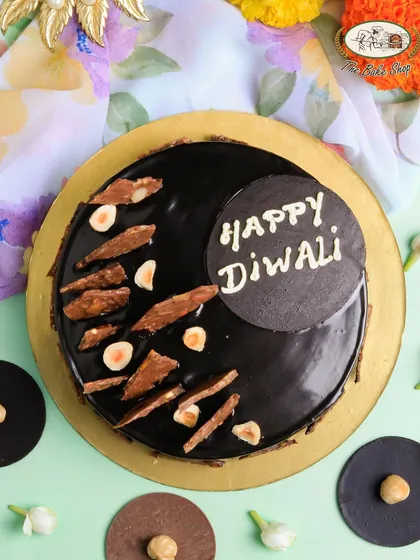 Celebrate Diwali with our indulgent Hazelnut Truffle Cake. This rich, glossy chocolate cake is topped with crunchy hazelnuts and a festive "Happy Diwali" message, offering a modern and luxurious centerpiece for your celebrations.