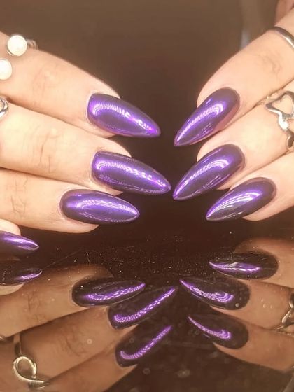 A bold and vibrant purple chrome manicure on sharp stiletto nails.