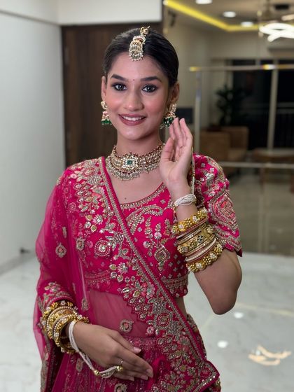 This bride is all smiles in her bright pink outfit. The makeup is kept fresh and radiant to match the joyful energy of the event.