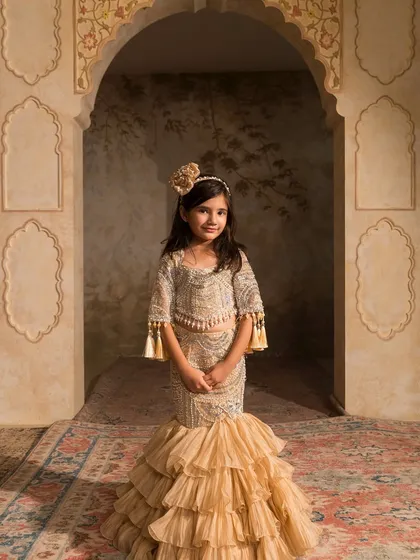 We love creating unique silhouettes like this golden mermaid style lehenga. The outfit features a fully beaded top with tassel sleeves and a dramatic ruffled fishcut skirt, blending traditional craft with a contemporary shape.