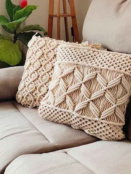 There's nothing like adding texture to a room with handmade cushion covers. These macrame pillow cases, shown here on a comfy sofa, feature two different intricate knot patterns. They are perfect for giving your living room or bedroom a cozy, boho-chic feel.