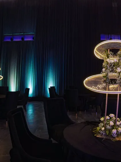 Modern illuminated centerpieces on black-clothed tables, creating a futuristic and chic look for a themed party.