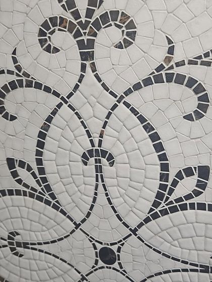 A detailed look at a black and white mosaic tile with an ornate, damask-style pattern. Perfect for creating a classic, high-contrast look.