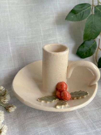 This classic candle holder, adorned with holly leaves and berries, is a simple and elegant piece to add to your Christmas decor.