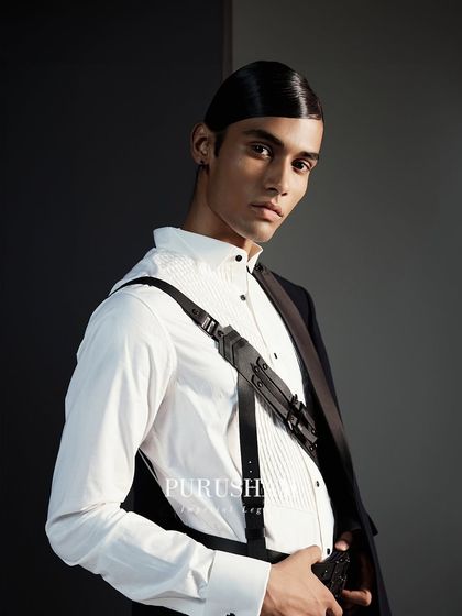 Complete your look with statement accessories that speak volumes. This leather harness, worn over a crisp white shirt, is a perfect example of my modern design philosophy.