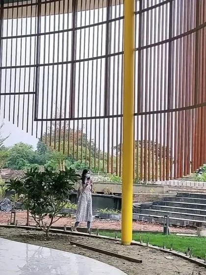 A beautiful, curved screen made from vertical wooden slats. This custom installation serves as a stunning architectural feature in a landscaped area, demonstrating our ability to work with complex shapes.