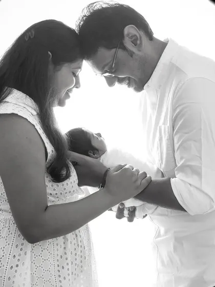 A beautiful black and white portrait of new parents admiring their baby. This high-contrast, backlit style creates a feeling of intimacy and awe.