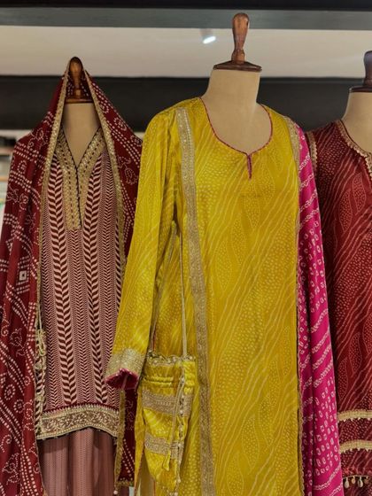 A collection of bandhani-inspired kurta sets in earthy red and bright yellow, featuring delicate gota patti work.