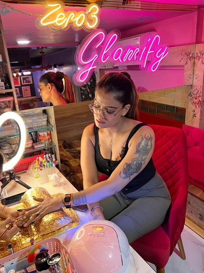 The perfect spot to get glam. A client enjoying her manicure session under our "Glamify" neon sign, capturing the stylish and modern vibe of our studio.