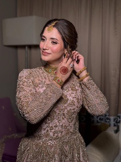 A candid moment of the bride putting on her earrings. This shot showcases the soft, romantic updo and the flawless makeup from a side profile, highlighting the clean lines and glowing skin.