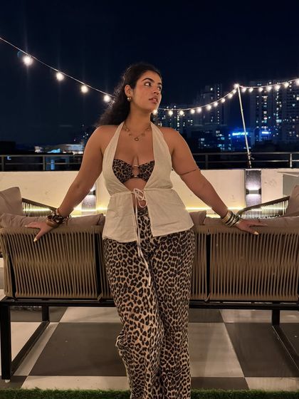 Another angle of my animal print outfit, showing how the pieces move. The string lights and city skyline create a perfect evening ambiance.
