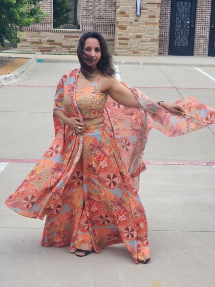 A vibrant and flowy three-piece set, perfect for a destination wedding or a summer party. It includes a printed crop top, flared palazzo pants, and a matching cape.