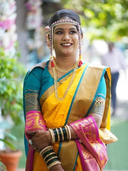 A three-quarter portrait of the bride, looking happy and radiant. The yellow saree and green bangles are iconic elements of the look.