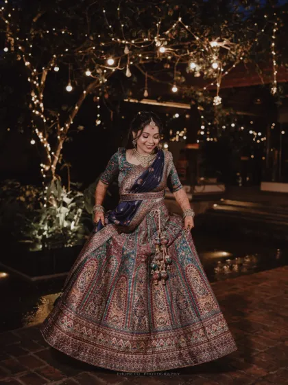 The bride twirls in her magnificent lehenga, the fairy lights creating a magical, dreamlike backdrop for this nighttime portrait.