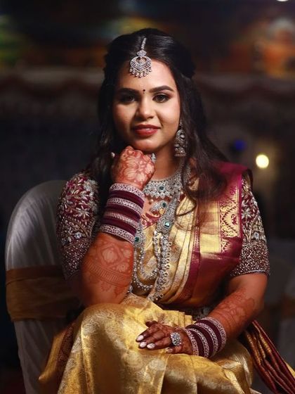 A poised and elegant bride, her hands gently resting on her lap, showcasing her beautiful henna.