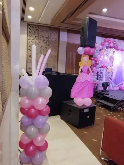 Balloon pillars with Barbie cutouts placed next to the DJ console, ensuring the theme is carried throughout the entire event space.