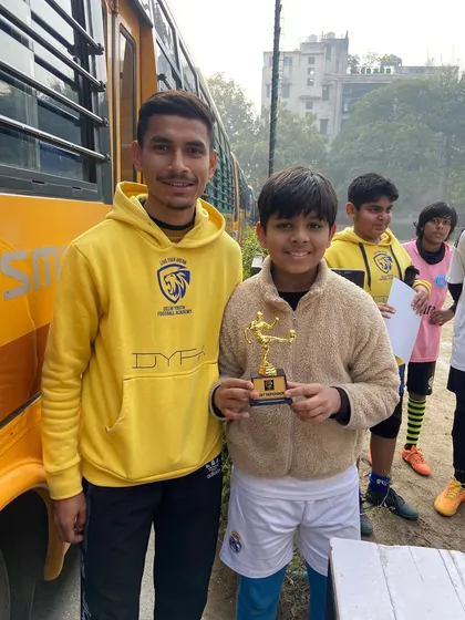 The life of a footballer is about collecting memories, medals, and trophies. A player proudly displays his award after a tournament.