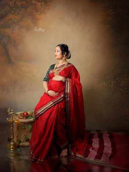 A quiet moment of reflection for this mother-to-be in a stunning red saree. The classic props and artistic lighting make this portrait feel like a timeless piece of art.