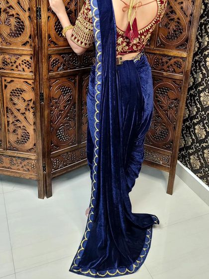 The back view of the velvet dhoti drape, showcasing the flowing pallu. The fabric is arranged to create a dramatic and elegant train effect.