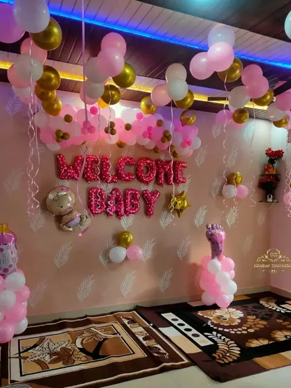 The "Welcome Baby" room decoration with pink, white, and gold balloons, viewed from a different angle.