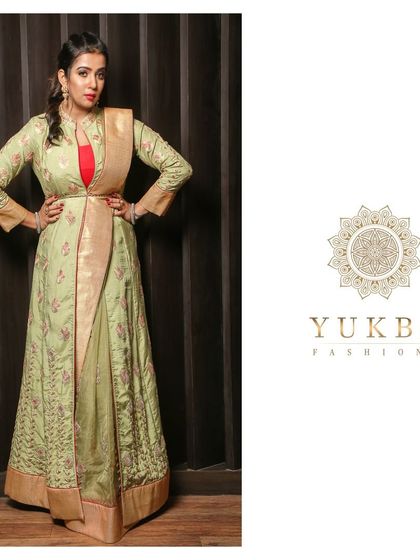 A full-length view of a pistachio green Anarkali gown. The gown features subtle floral embroidery and is paired with an attached dupatta-style drape for a sophisticated, modern silhouette.