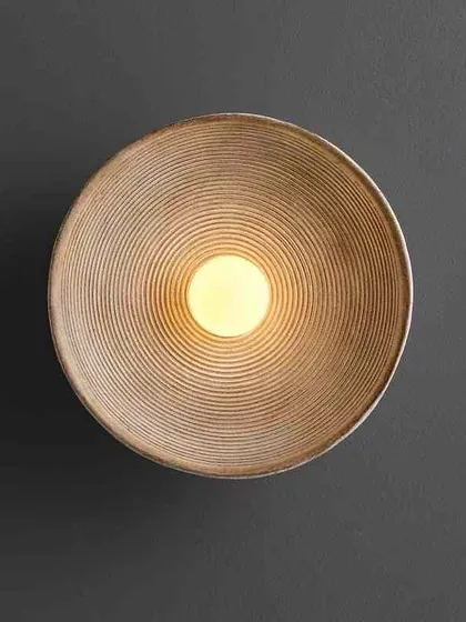 A minimalist bowl-shaped wall sconce with a concentric ring pattern. This design creates a soft, diffused glow, perfect for creating a calming atmosphere.