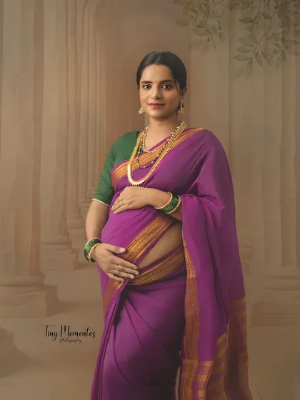 Dressed in a vibrant purple Mysore silk saree, this portrait captures the regal elegance and quiet strength of a mother-to-be.