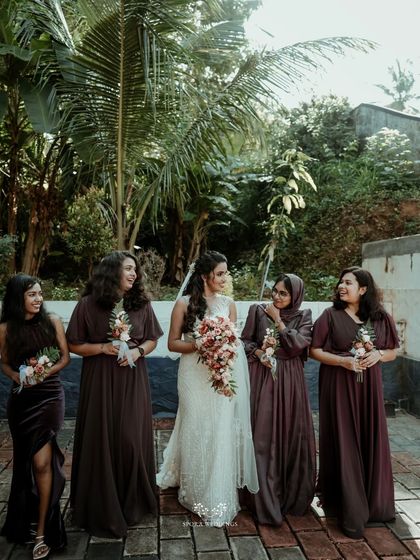 The bride sharing a laugh with her bridesmaids, all dressed in coordinating deep purple gowns. I help coordinate bridal party attire to create a cohesive look.